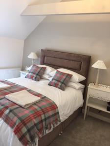 a bedroom with a bed with a plaid blanket and pillows at The Golden Mile Country Inn in Ewenny