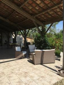 un patio avec des chaises blanches sous un toit en bois dans l'établissement Chambre d'Hotes Cugnac, à Sainte-Sabine