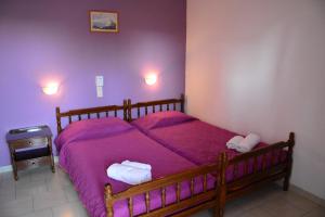 a bedroom with a wooden bed with purple sheets at Voula Apartments in Agia Marina Aegina