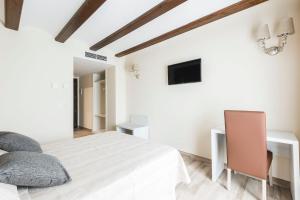 a white bedroom with a bed and a desk at Hotel Atiana in Albarracín