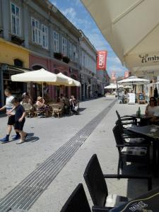 a street with tables and chairs and people sitting at tables at Studio Jolie in Novi Sad
