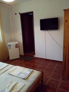 チェルノモレツにあるTopalovi Guest Houseのベッド1台と壁掛けテレビが備わる客室です。