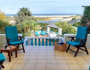 a balcony with blue chairs and a view of the ocean at Mont Fleur B&B in Wilderness