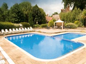 a swimming pool with chairs and a gazebo at Macdonald Elmers Court Hotel in Lymington