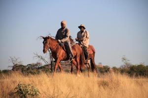 dos hombres montando caballos en un campo de hierba alta en Tantebane Game Ranch, en Tantebane