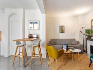 uma sala de estar com um sofá, uma mesa e cadeiras em Welkeys - St Honore em Paris