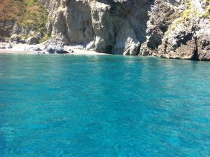un cuerpo azul de agua junto a una playa rocosa en Golfo di Tindari Apartments, en Falcone