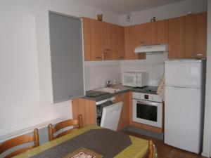 a kitchen with a white refrigerator and a table at 31 avenue GEORGES CLEMENCEAU in Le Mont-Dore