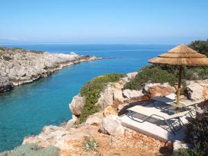 a beach with chairs and an umbrella and the ocean at Giorgi's Blue Apartments in Kalathas