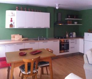a kitchen with white cabinets and a table and chairs at ELDA's Home - Ideale per famiglie in Pinzolo