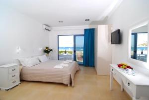 a white bedroom with a bed and a desk and windows at Kordistos Hotel in Kefalos