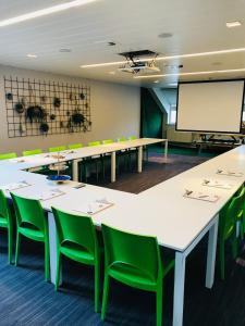 a conference room with tables and green chairs and a screen at Eurotel Lanaken in Lanaken
