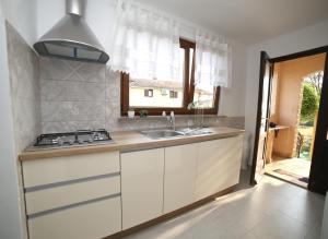 a kitchen with white cabinets and a sink and a window at Garden in Pula +10 photos