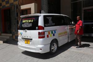 ダル・エス・サラームにあるレインボー ホテルの白いバンの横に立っている男