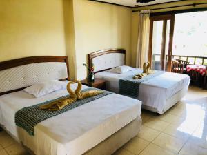 two beds in a room with two swans on them at Padangbai Beach inn in Padangbai