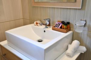 a white sink in a bathroom with a mirror at Hotel Manthos Blue in Agios Ioannis Pelio