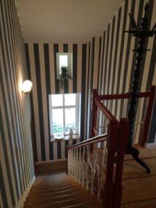 a hallway with a staircase with striped walls and a window at Traumparadies in Bad Sulza