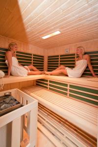 dos mujeres sentadas en literas en una sauna en Pleschinhof en Velden am Wörthersee