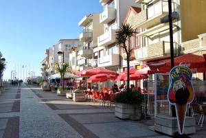 a street with tables and chairs and umbrellas at Casa do gato branco in Furadouro