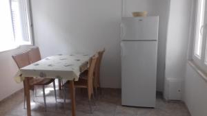 a kitchen with a table and a white refrigerator at Apartments Pavla in Orebić