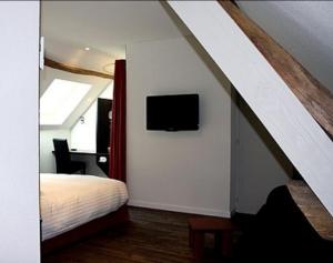 een slaapkamer met een bed en een tv aan de muur bij Hôtel Barbier des Bois in Bruailles