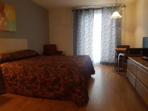 a bedroom with a bed and a desk and a window at Motel les Pignons Verts in Gatineau