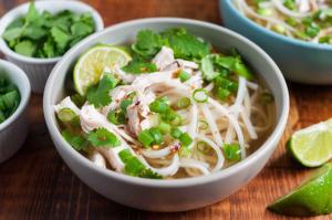 a bowl of chicken noodle soup with lime slices and cilantro at Phat Dat Hotel in Quảng Ngãi