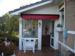 eine Veranda eines Hauses mit einer roten Markise in der Unterkunft Graf Luckner Hüs in Scharbeutz