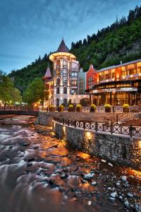 a large building next to a river at night at Crowne Plaza - Borjomi, an IHG Hotel in Borjomi