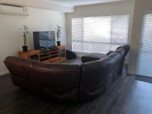 uma sala de estar com um sofá de couro e uma televisão em Falcon Bay 4x4 Townhouse em Wannanup