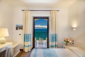 a bedroom with a view of the ocean at Hotel Dei Pini in Alghero