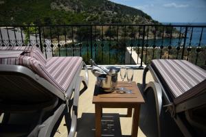 a balcony with two chairs and a table with wine glasses at Thassos Grand Resort in Alyki