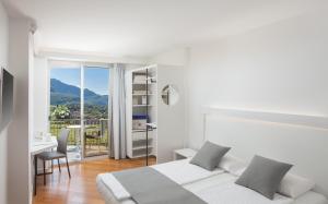 a hotel room with a bed, desk and a tv at Hotel Continental - TonelliHotels in Nago-Torbole
