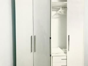 a white closet with three doors and a desk at EKA Luxury One-Bedroom Apartment in Durrës