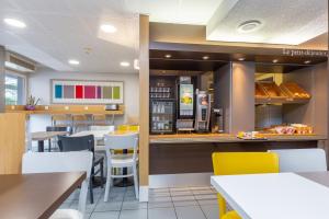 a restaurant with white tables and yellow chairs at B&B HOTEL Bayonne in Bayonne