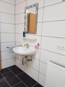 a white bathroom with a sink and a mirror at Jujhar's Gästehaus in Wasserburg am Inn