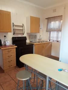 uma cozinha com uma mesa, um lavatório e um fogão em Oppi Rotse Guesthouse em St. Lucia