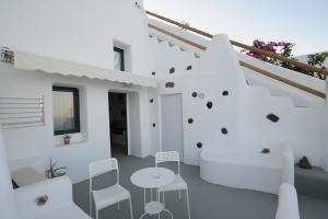 Habitación blanca con sillas, mesa y escaleras en Manias Fira Residences, en Fira