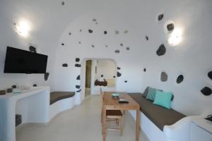 a living room with a couch and a tv on a wall at Manias Fira Residences in Fira