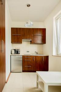 a kitchen with wooden cabinets and a white floor at Apartament Kniaziewicza - Komfortowe Noclegi in Piaseczno
