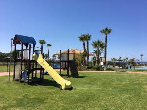 un parque infantil con tobogán en un parque con palmeras en Atlanterra Playa, en Zahara de los Atunes