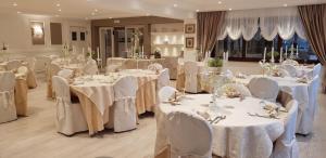 a banquet hall with white tables and white chairs at Hotel Edelweiss in Pescasseroli