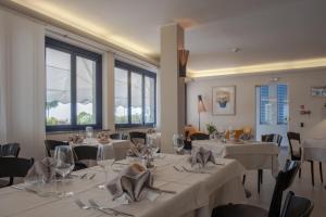 a dining room with white tables and chairs and windows at Hotel Sirenetta in Grado