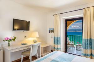 a hotel room with a desk and a view of the ocean at Hotel Dei Pini in Fertilia