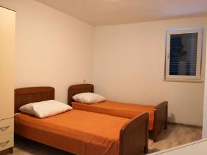 zwei Betten in einem kleinen Zimmer mit Fenster in der Unterkunft Apartments Jaksic in Postira