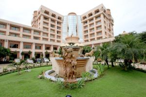 a fountain in the grass in front of a building at Hotel Swosti Premium Bhubaneswar in Bhubaneshwar