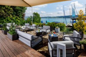 a patio with chairs and tables and a view of the water at Hallwil Swiss Quality Seehotel in Beinwil