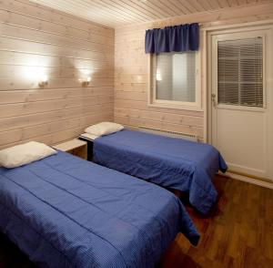 two beds in a room with wooden walls at Himosport Apartments in Jämsä