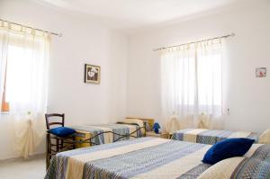 4 camas en una habitación con paredes y ventanas blancas en Casa Campanina, en Agropoli