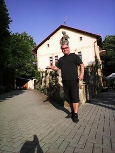 un hombre está parado frente a un edificio en U Zlate Brany Cesky raj en Libuň
